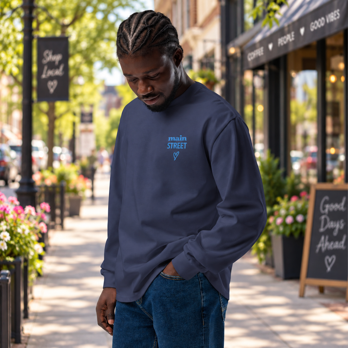 Man wearing long-sleeve t-shirt with words "Main Street" standing with hand in pocket on a downtown street